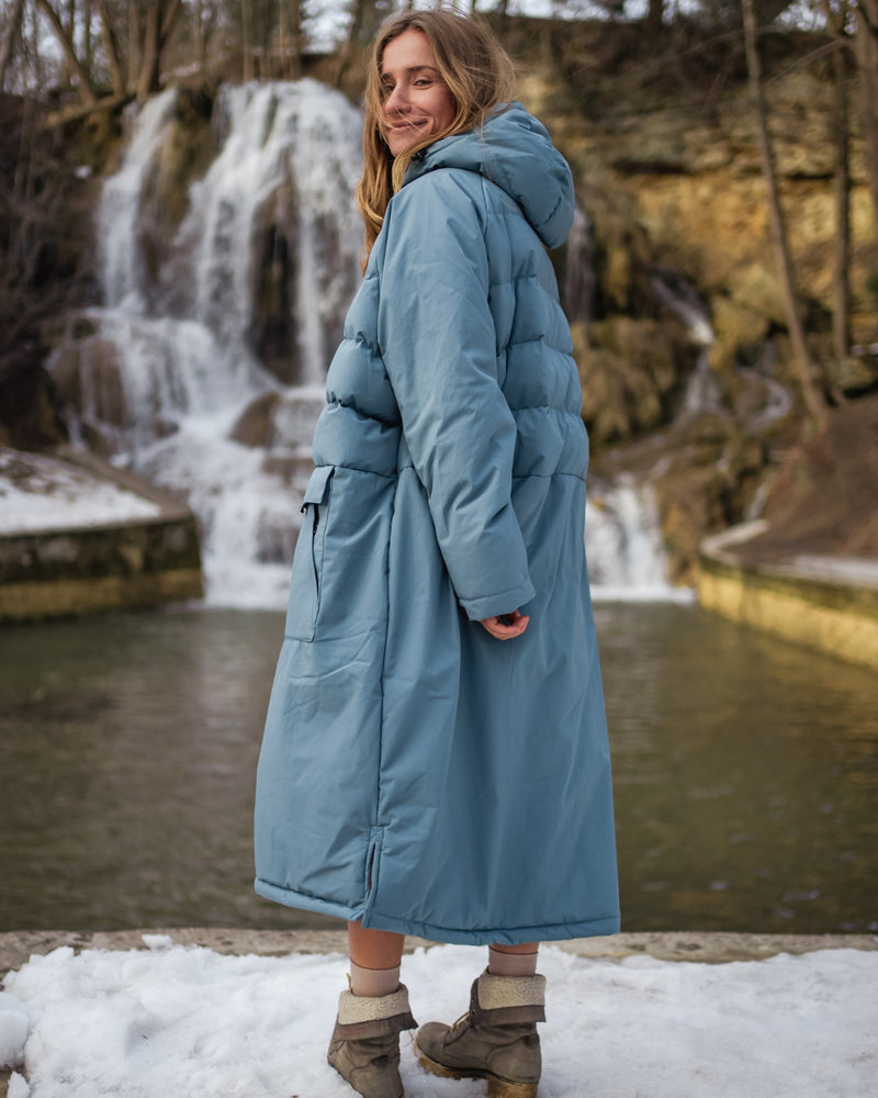 Back of woman wearing a Vivida All Weather Puffer Changing Robe in Mineral Blue