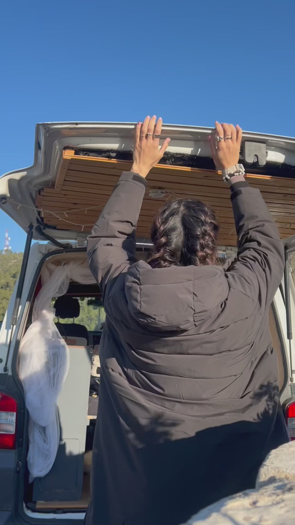 Woman dances in her Vivida Lifestyle Puffer Changing Robe on a surf trip in a campervan